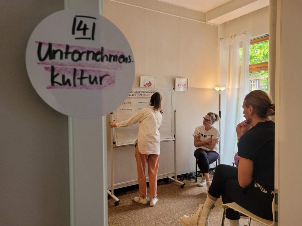 Personen diskutieren vor einem Whiteboard im Seminarraum.